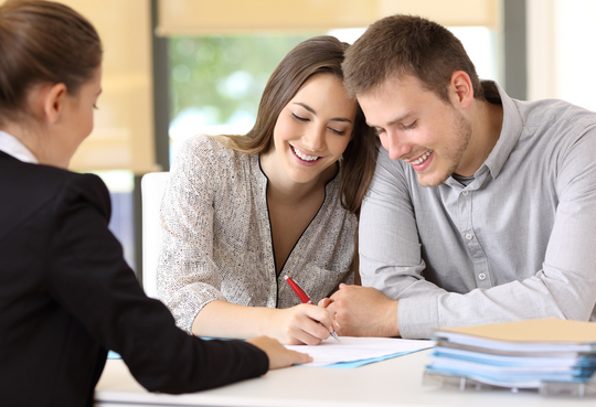 Happy couple signing a contract at office